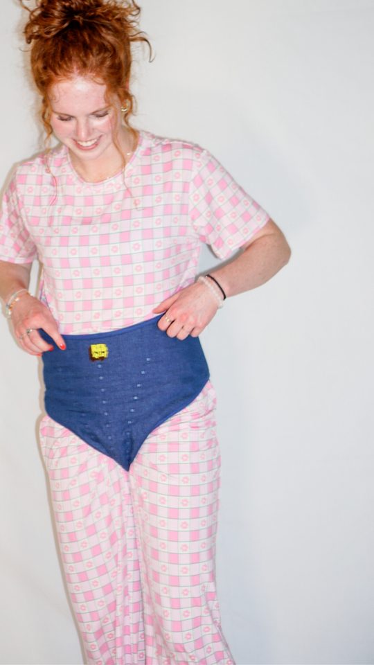 Woman in pink pajamas adjusting a navy REB heating pad